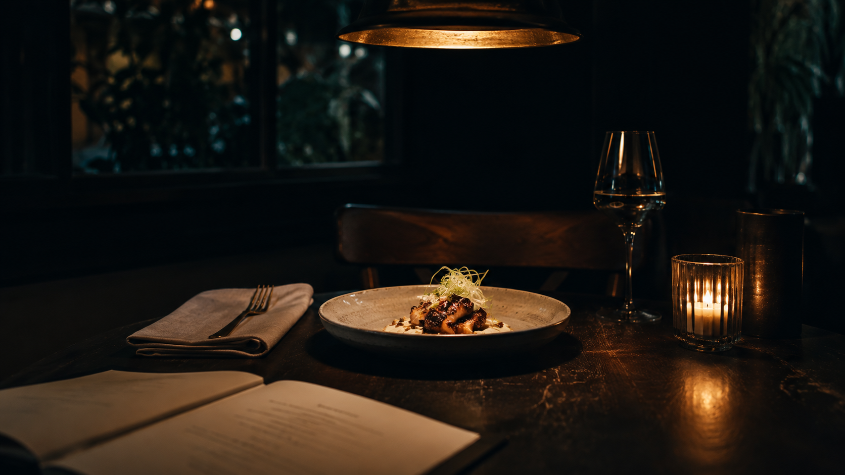 Candle-lit Berlin restaurant table at night — plated dish, linen napkin, brass cutlery, single tungsten pendant