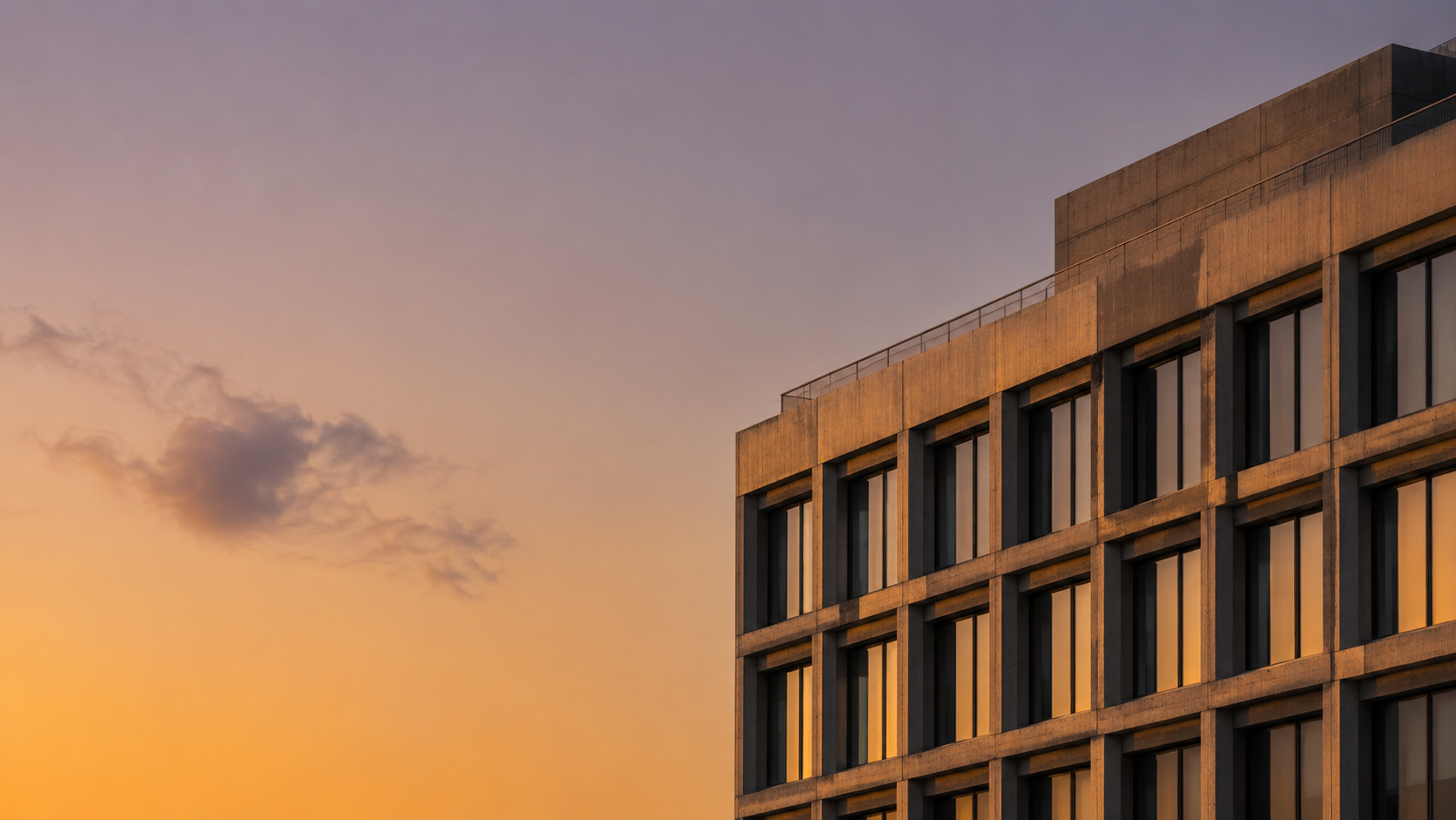 Golden-hour Berlin commercial property — warm amber sunset sky, sandstone façade, modular window grid